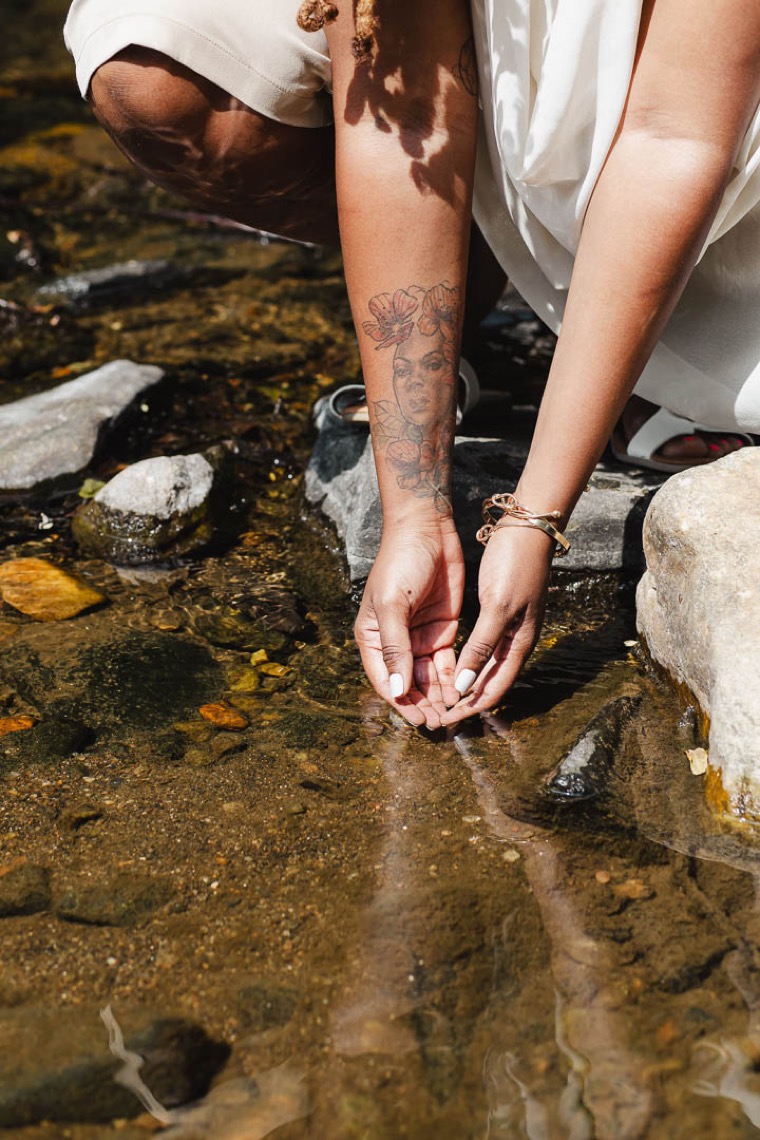 Charika White's hands reaching into clear creek water, the clarity an adult ADHD diagnosis brings