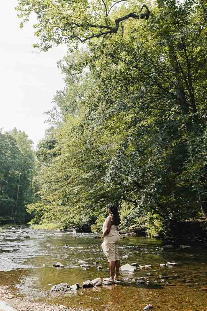 Charika White standing on stones at a Maryland creek, telehealth therapy reaching Baltimore and beyond