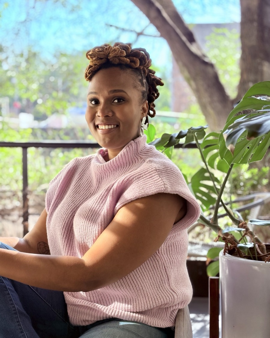 Charika White, licensed Black female therapist in Washington DC, smiling warmly on a plant-filled balcony