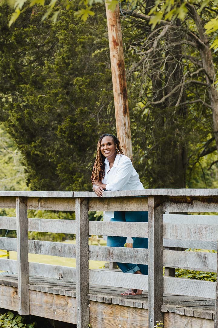 Charika White LICSW leaning on a wooden footbridge, culturally affirming Black therapist for Washington DC clients