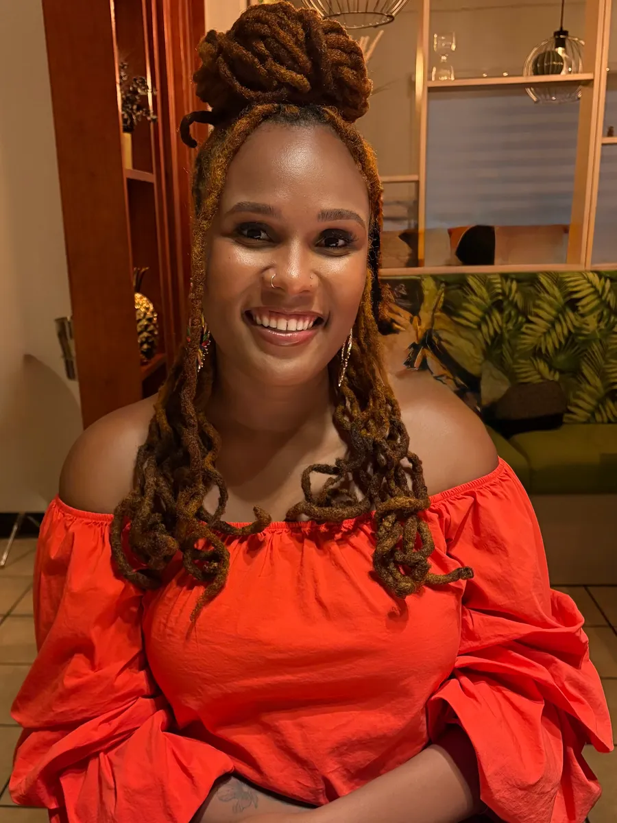 Charika White, psychotherapist and author of Island Mind, Foreign Ground, smiling in a coral off shoulder top