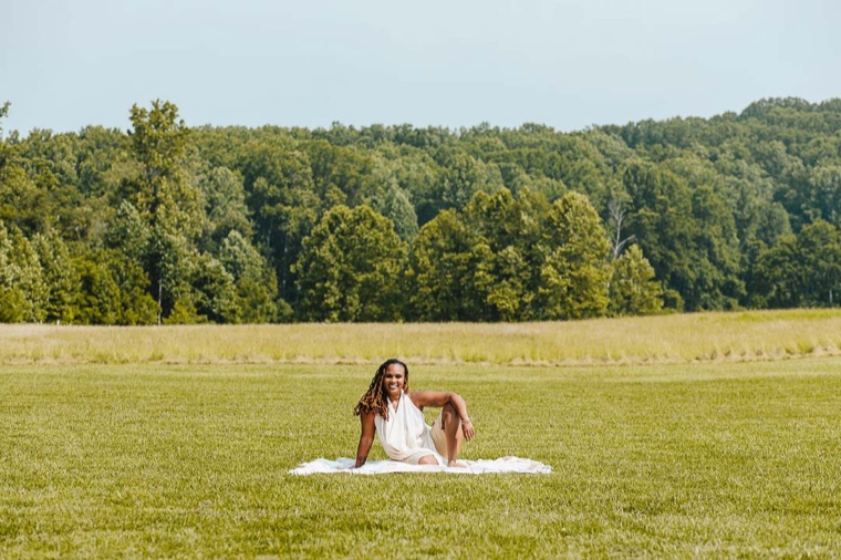Charika White relaxing on a picnic blanket in a Maryland field, the space to exhale her holistic mental health support creates