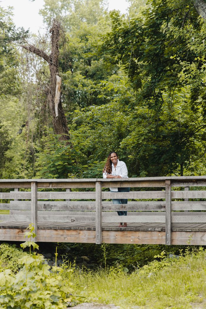 Charika White smiling from a wooden footbridge in Maryland, the Black therapist adults in DC and Maryland contact at Life Migration Therapy