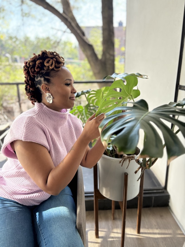 Charika White tending monstera plants in the sun, the warm virtual therapy space DC and Maryland clients contact her from