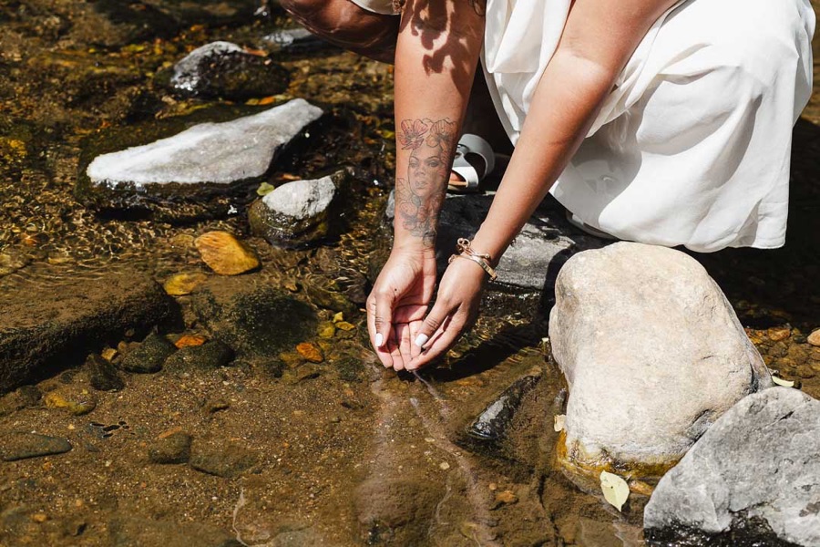 Charika White's hands cupping clear creek water, a grounding image for trauma-responsive therapy with a Black therapist in DC