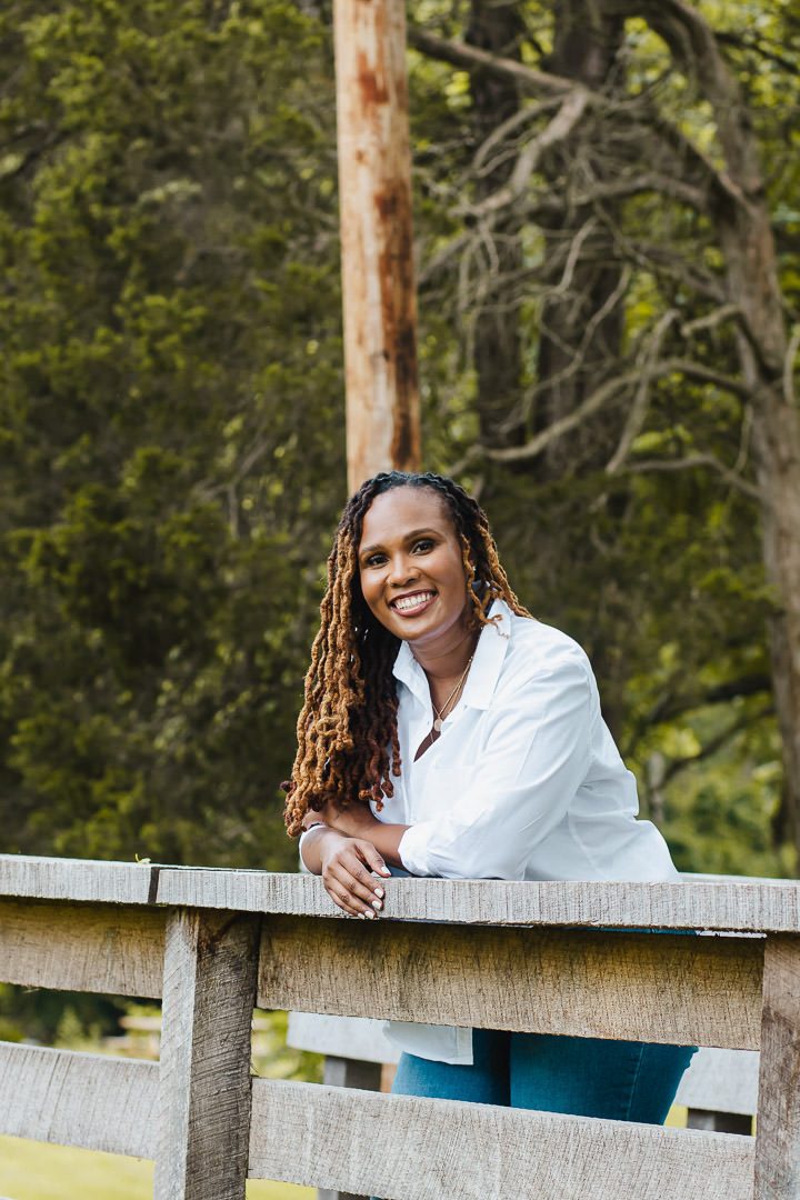 Charika White leaning on a wooden fence, queer affirming therapist serving Washington DC adults