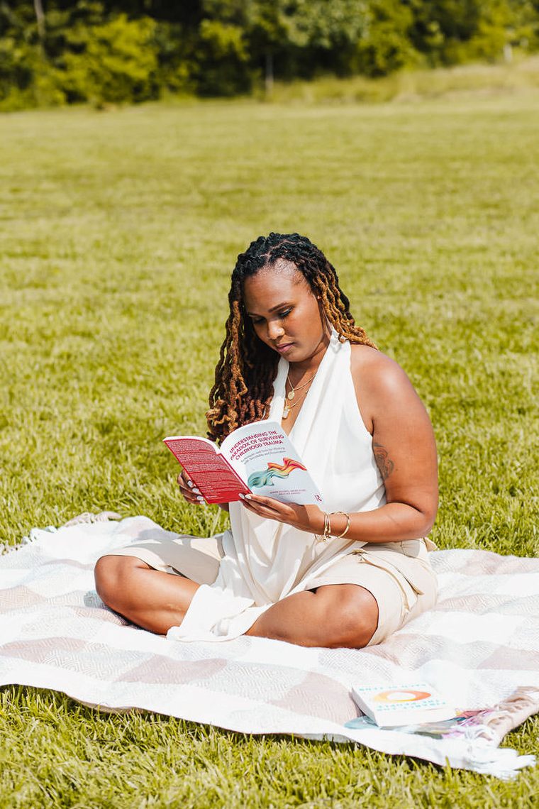 Charika White reading on a blanket in a Maryland field, reflective approach to LGBTQ affirming therapy