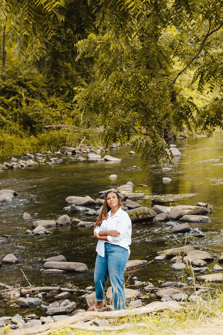 Charika White standing at a Maryland creek, queer Black immigrant therapist for LGBTQ adults statewide