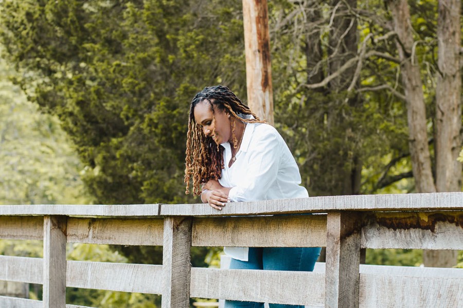 Charika White pausing on a wooden bridge in Maryland, weighing the self pay therapy decision DC and Maryland clients bring to Life Migration Therapy