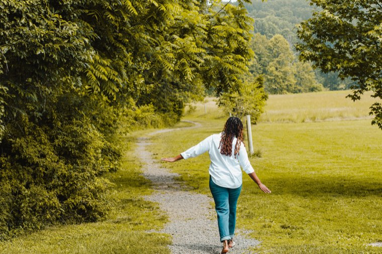 Charika White walking a winding Maryland path with arms out, the flexible path sliding scale fees open for DC therapy clients