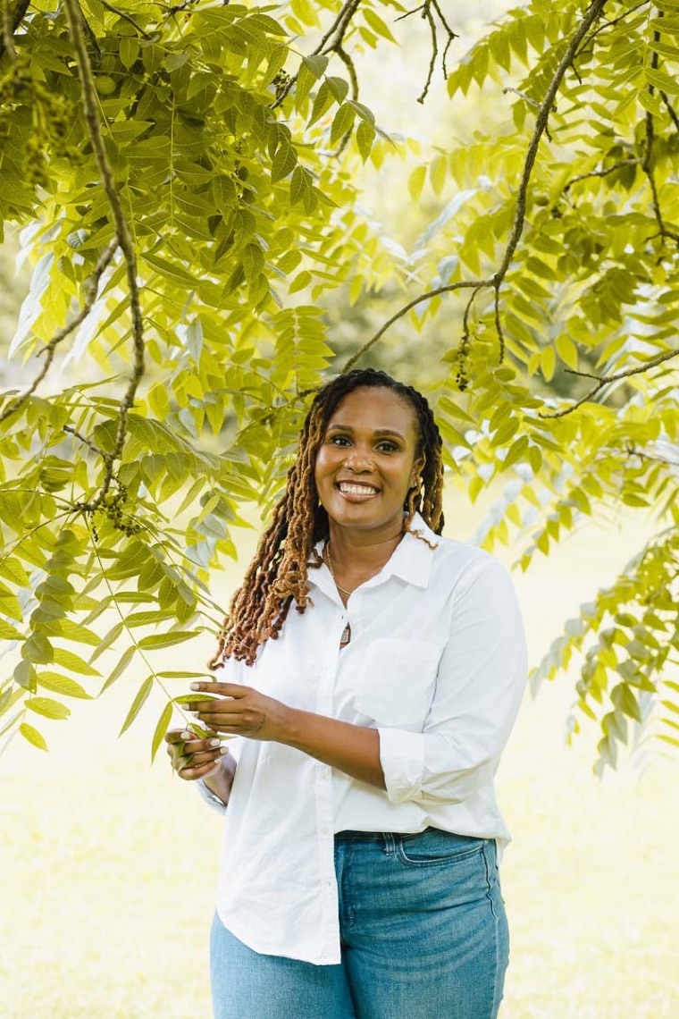 Charika White under green walnut leaves, the supervisor social workers in DC and Maryland train with at Life Migration Therapy