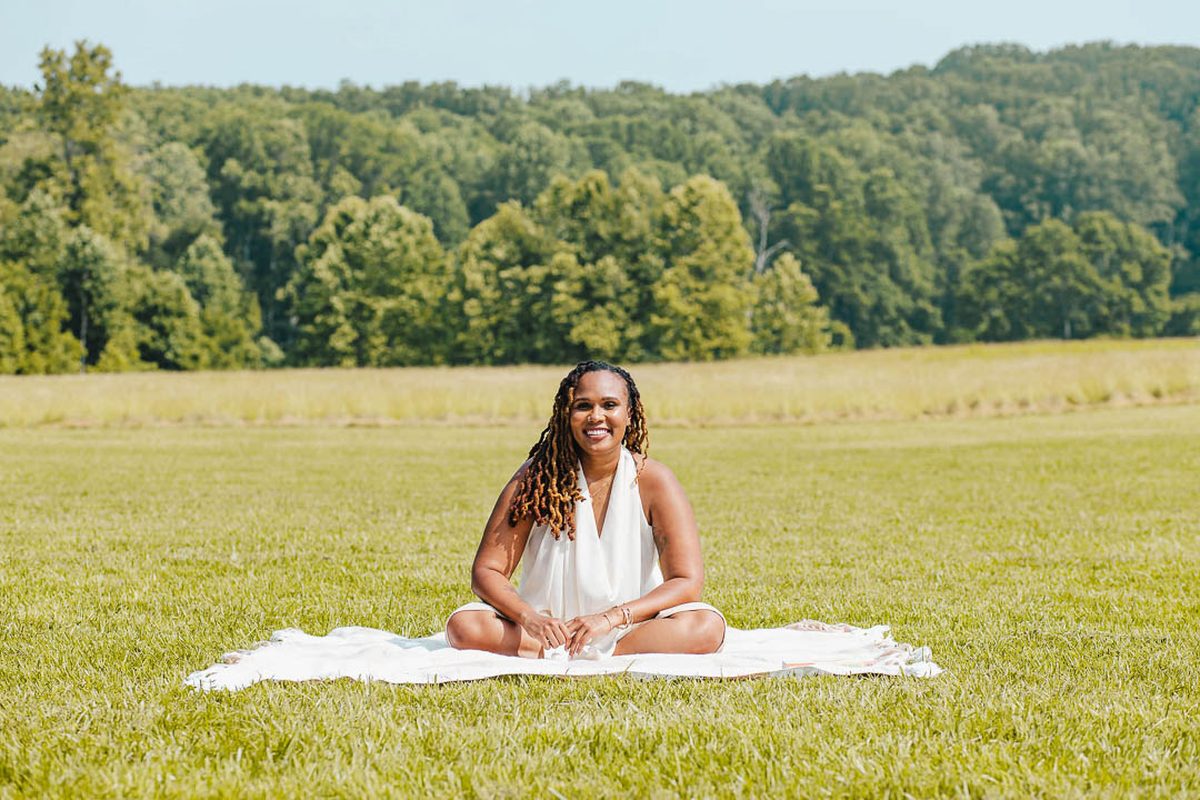 Charika White sitting in a wide open field, workplace wellbeing programs for Maryland and DC organizations